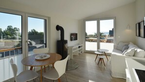 Un salon moderne doté d’une cheminée, d’un coin repas et de grandes fenêtres offrant une vue sur l’extérieur.