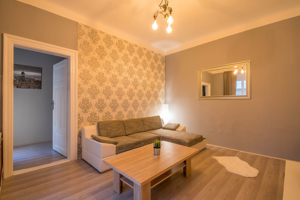 Ein Wohnzimmer mit Ecksofa, Couchtisch, Lampe und einem Spiegel an der Wand.