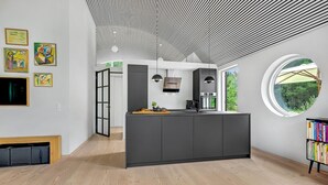 A modern kitchen with a central island, a large window, and artwork on the walls. - 2 bedroom amazing home in Vig (Vig)