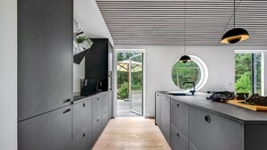 A modern kitchen with a wooden floor, grey cabinetry, and a large window overlooking a garden. - 2 bedroom amazing home in Vig (Vig)