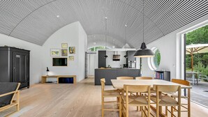 A modern interior with a dining area, kitchen, and open space with a unique ceiling design. - 2 bedroom amazing home in Vig (Vig)