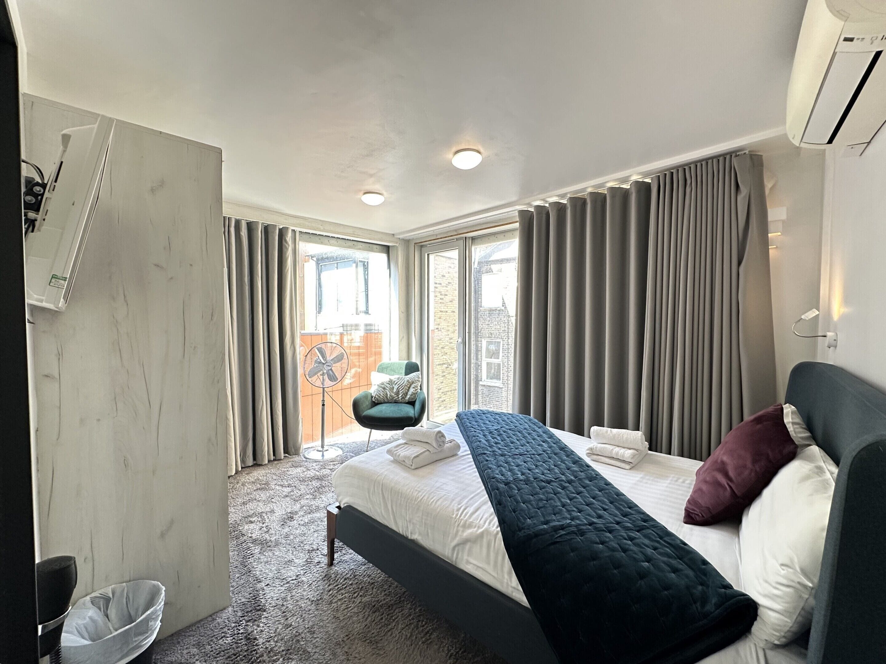 Ein modernes Hotelzimmer mit Bett, Stuhl, Fenster und Balkon.
