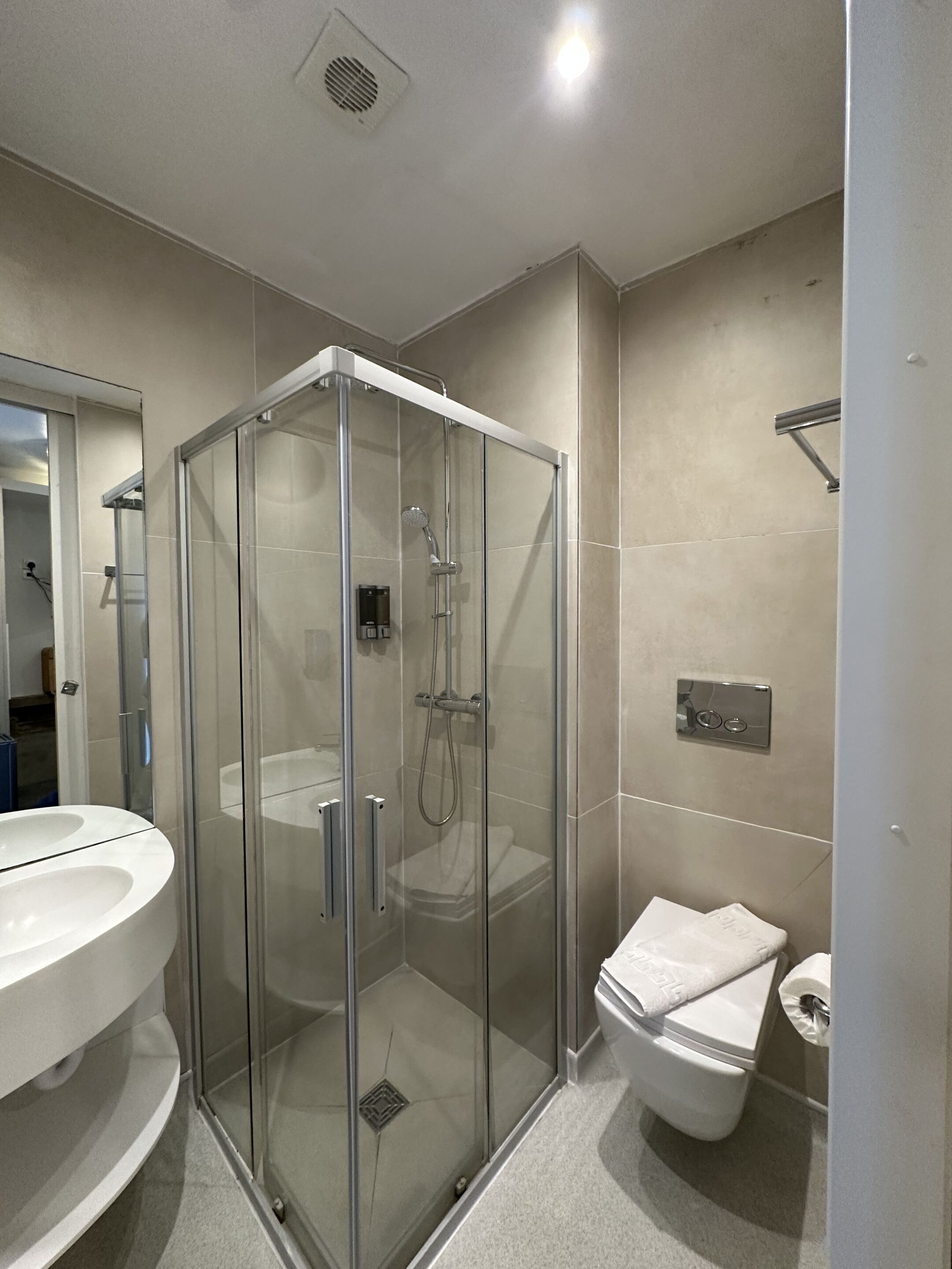 Une salle de bain moderne avec une douche à parois de verre, un lavabo blanc et des toilettes.