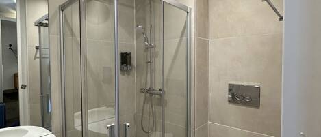 A modern bathroom with a glass-enclosed shower, a white sink, and a toilet.