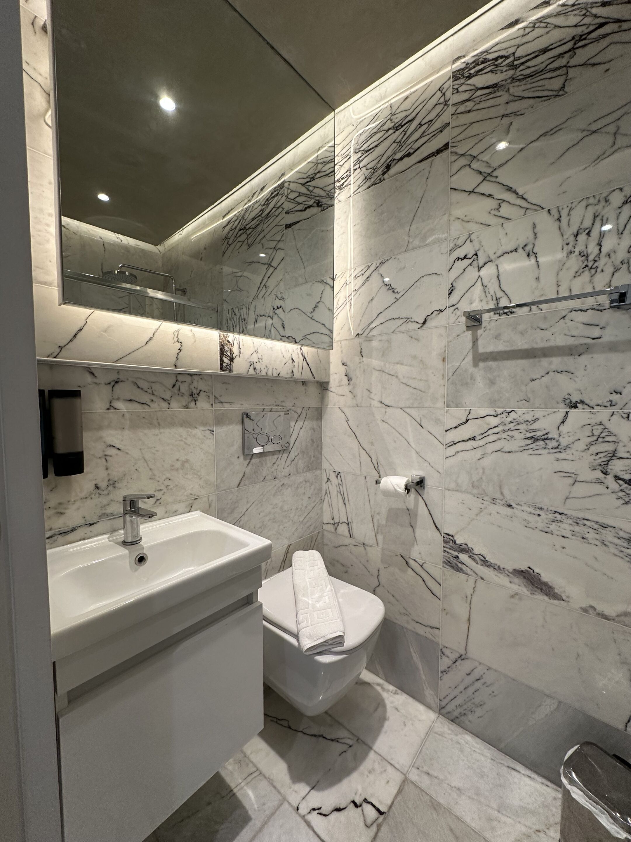 Ein modernes Badezimmer mit Marmorwaschbecken, Toilette und Duschbereich.