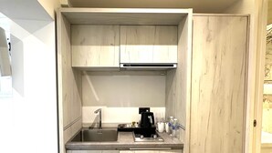 A compact kitchenette with a built-in sink, a coffee maker, and a microwave. - Widegate Residential (London)