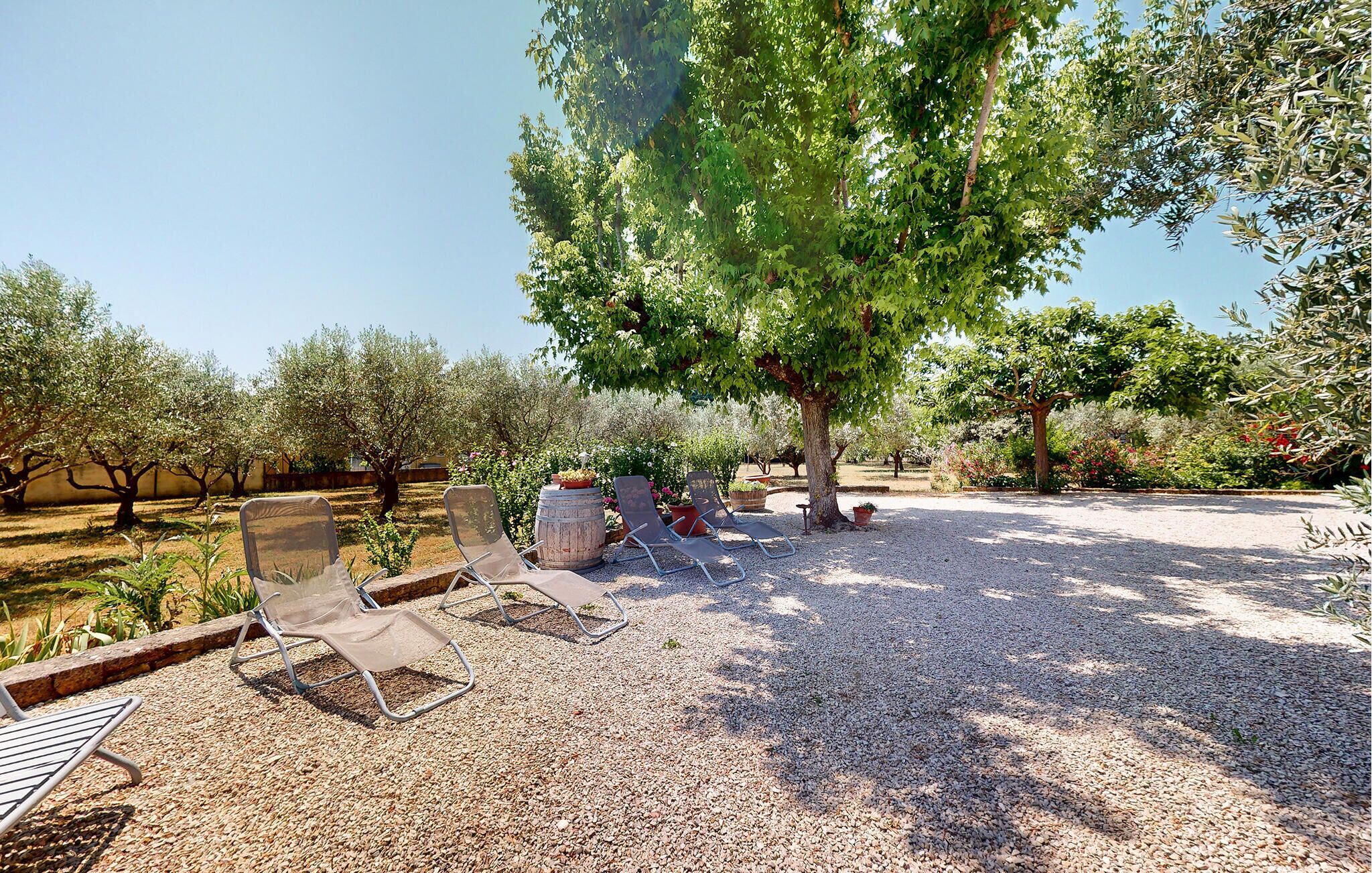 A gravel patio with outdoor seating and trees.