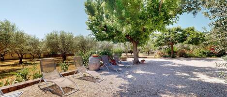 A gravel patio with outdoor seating and trees.