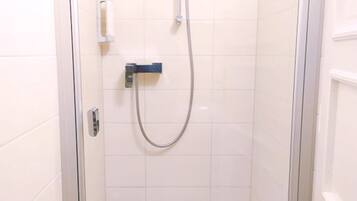 A small, enclosed shower stall with a handheld showerhead and a control panel.