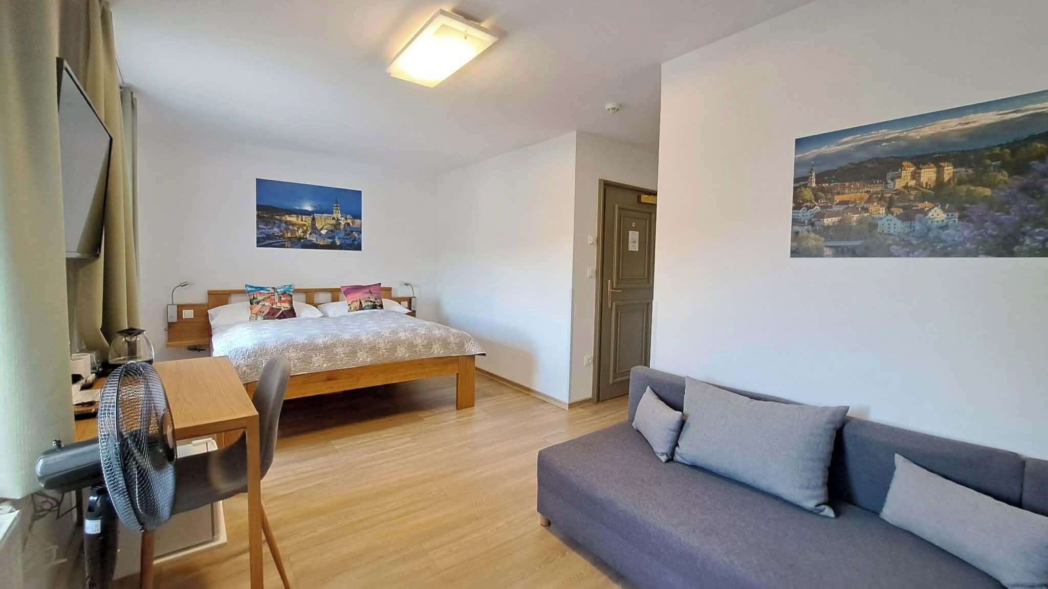 Une chambre à coucher comprenant un lit, un bureau avec une chaise, un canapé et deux tableaux accrochés au mur.