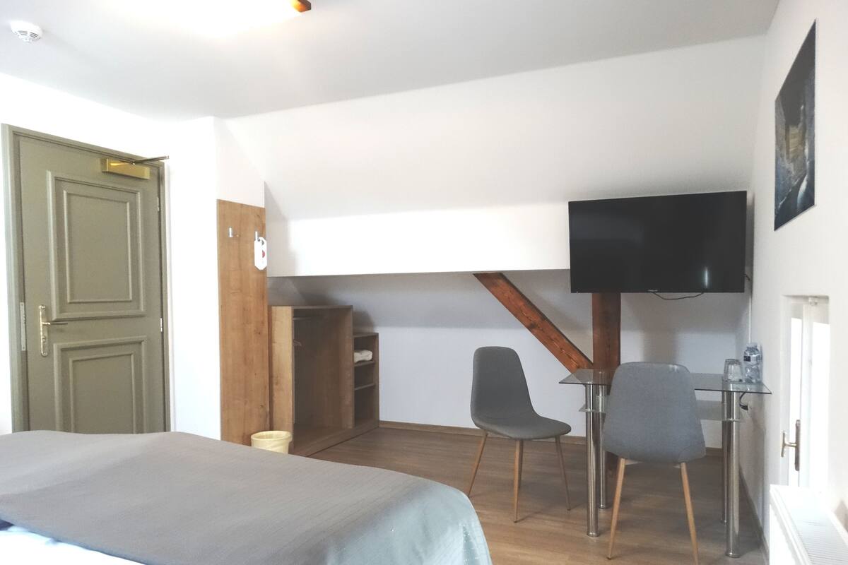 A room with a bed, a desk with a chair, a television, and a wardrobe.