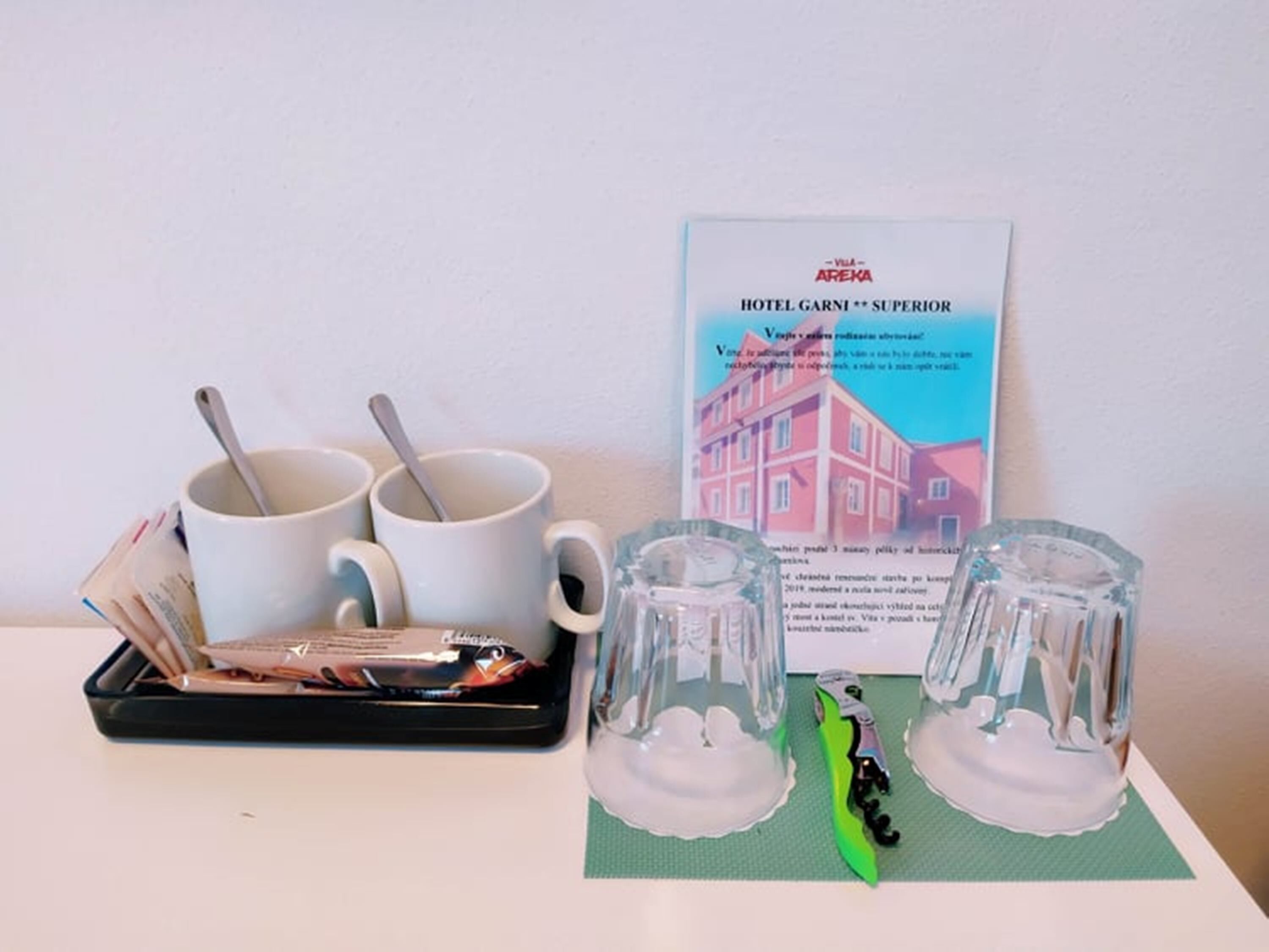 A hotel room with a breakfast tray, two mugs, and a menu.
