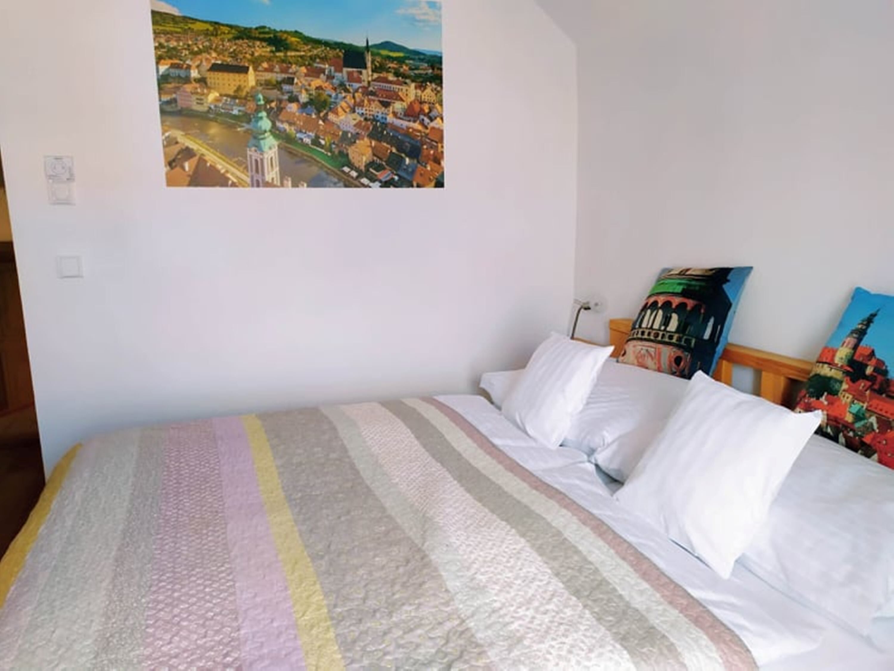 Una habitación de hotel con una cama, un cuadro de un paisaje urbano en la pared y un cartel de un edificio.