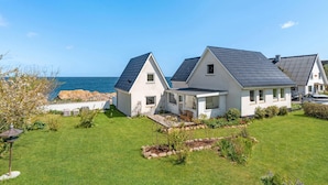 Una casa sul lungomare con un giardino erboso e vista mare.