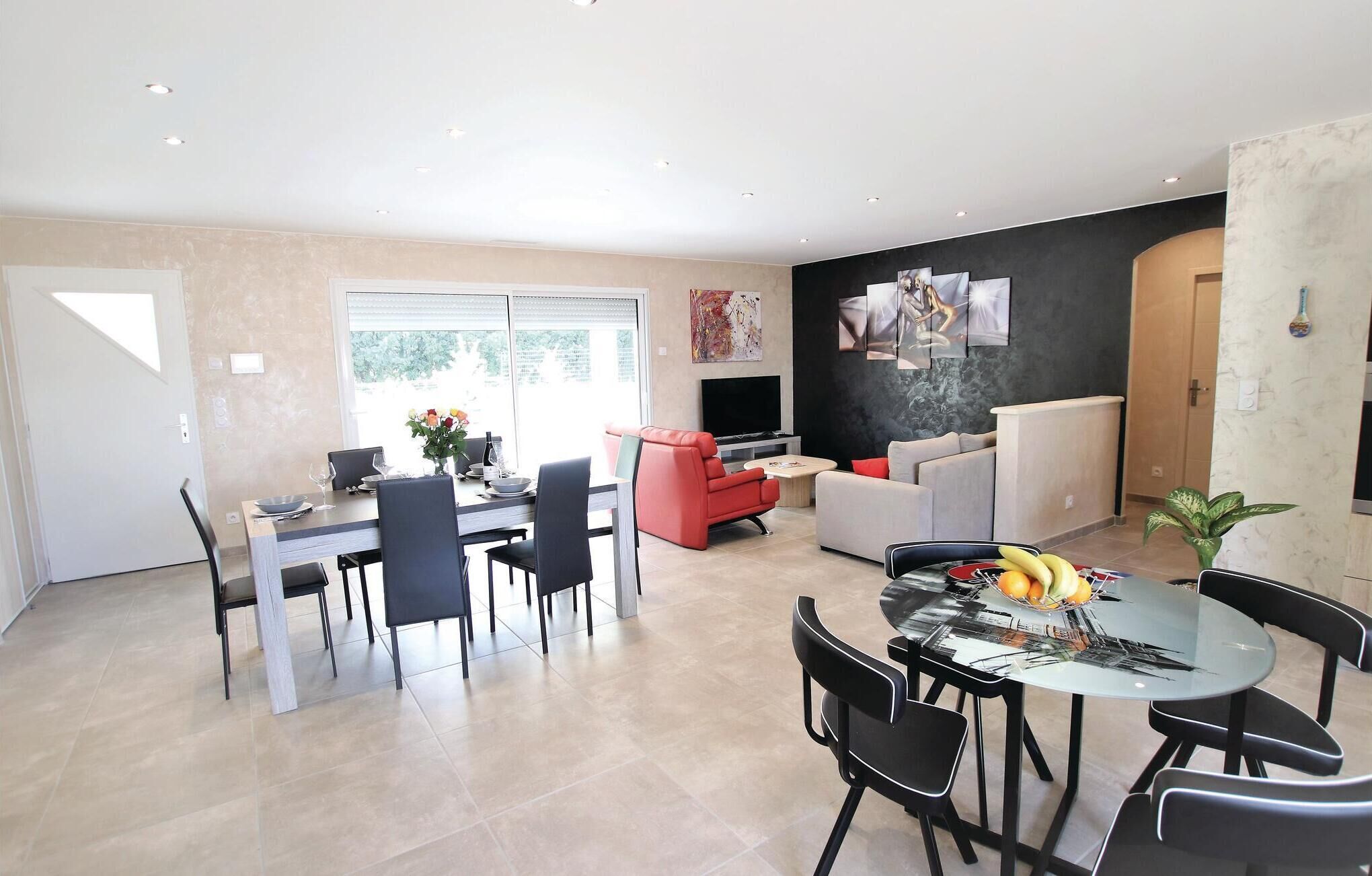 Ein moderner Wohnraum mit Essbereich, einer Couch, einem Fernseher und Kunstwerken an der Wand.