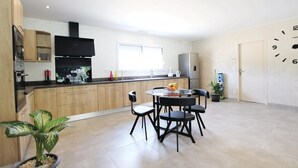 Een moderne keuken met houten kastjes, een zwarte afzuigkap en een eethoek met een ronde tafel en vier stoelen.