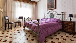 A bedroom with a metal bed frame, a purple bedspread, a wooden nightstand, and a chair. - La Villa (Pratola Peligna)