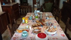 A dining table set with various food items and utensils, surrounded by wooden chairs and a floral tablecloth. - La Villa (Pratola Peligna)