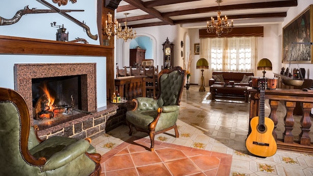 A traditional living room with a fireplace, leather armchairs, a dining area, and a guitar. - La Villa (Pratola Peligna)
