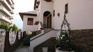 A courtyard with a stone staircase leading to a second floor, surrounded by white walls with red window frames and flower boxes. - La Villa (Pratola Peligna)