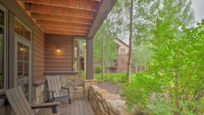 Une terrasse en bois avec des fauteuils Adirondack, un mur en pierre et une vue sur les bâtiments voisins.