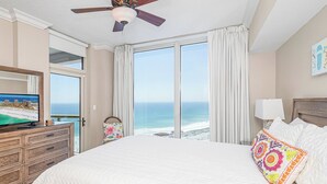 Une chambre d’hôtel avec un grand lit, un ventilateur de plafond, une télévision et une vue sur l’océan.