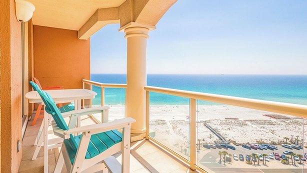 Un balcon donnant sur la plage, une table avec des chaises et une rambarde.