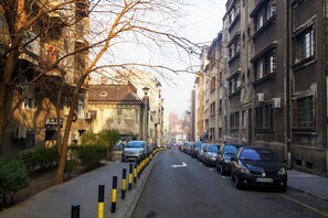 A narrow urban street lined with parked cars and buildings.