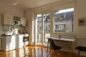 A modern kitchen with white cabinets, a microwave, and a dining area with a table and chairs.