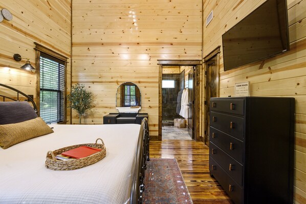 Un dormitorio de cabaña de madera con cama, cómoda y televisor.
