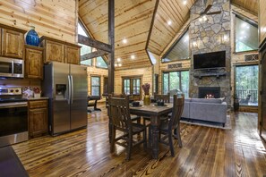 A spacious kitchen with wooden cabinets, a stainless steel refrigerator, and a dining area with a wooden table and chairs.
