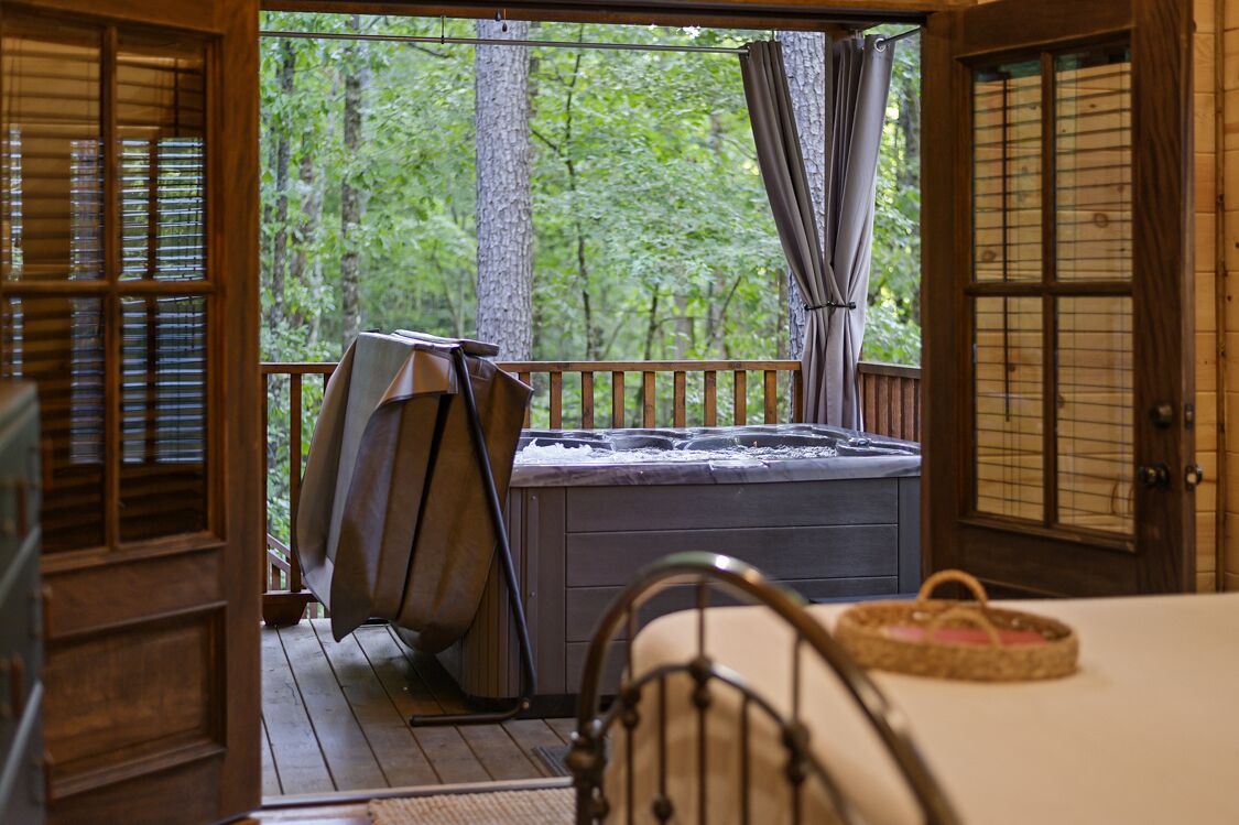 A hot tub on a wooden deck with a view of a forest.