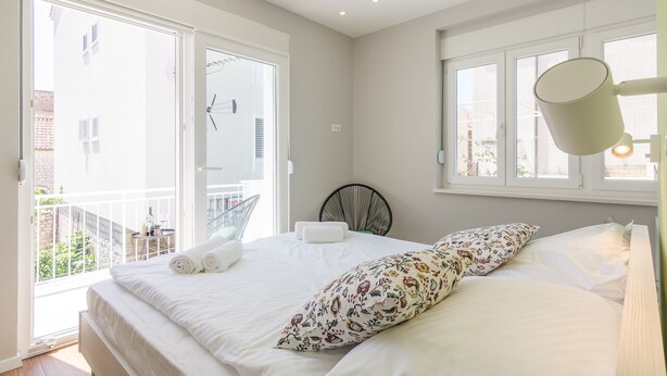 A bedroom with a bed, a chair, a window, and a balcony. - 4 Elements Old Town Views Rooms (Trogir)