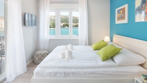 A hotel room with a large bed, two pillows, a TV, a window with a view of the sea, and artwork on the wall. - 4 Elements Old Town Views Rooms (Trogir)