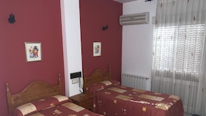 A room with two beds, a radiator, an air conditioner, and a window with curtains. - Hostel Restaurant Leyvamar (Guadahortuna)