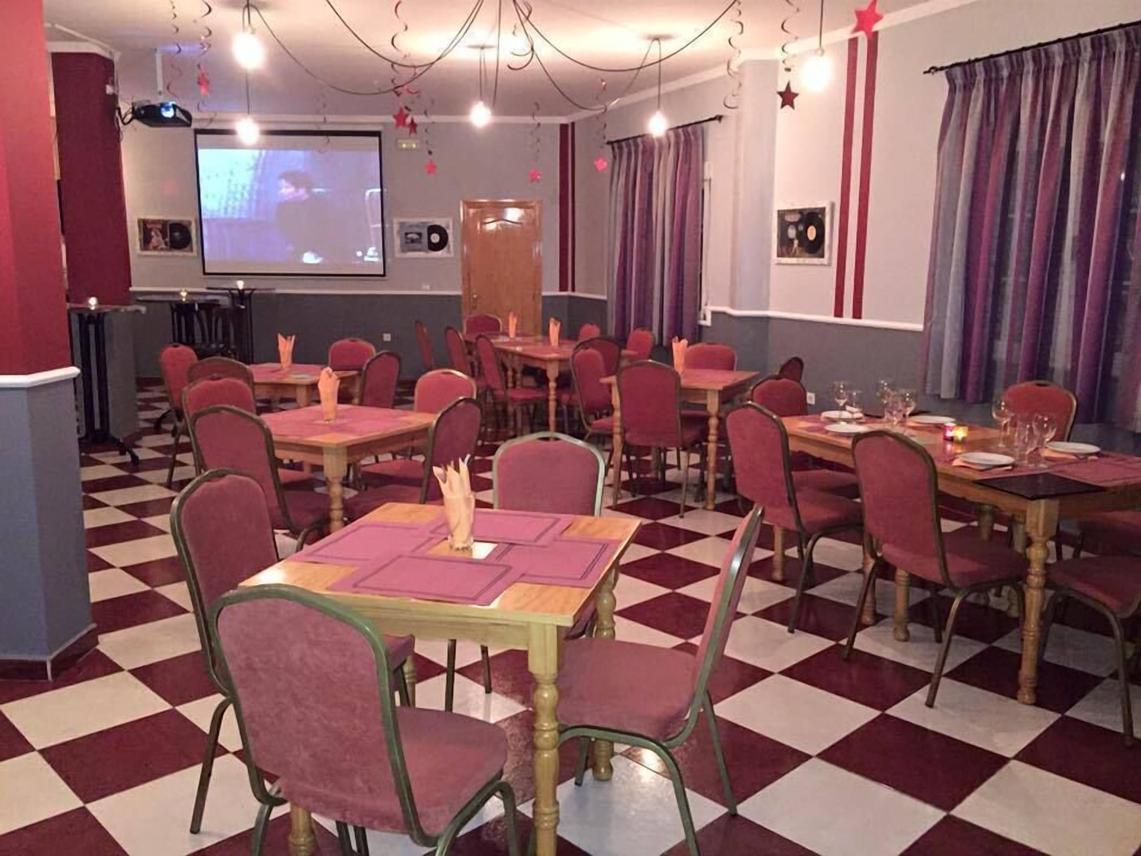A dining area with checkered flooring, red chairs, and tables set for a meal.