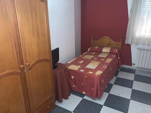 A bedroom with a checkered floor, a wooden bed, a red wall, and a wooden wardrobe. - Hostel Restaurant Leyvamar (Guadahortuna)