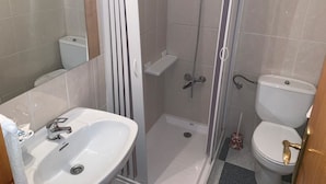 A bathroom with a white sink, a toilet, and a glass-enclosed shower area. - Hostel Restaurant Leyvamar (Guadahortuna)