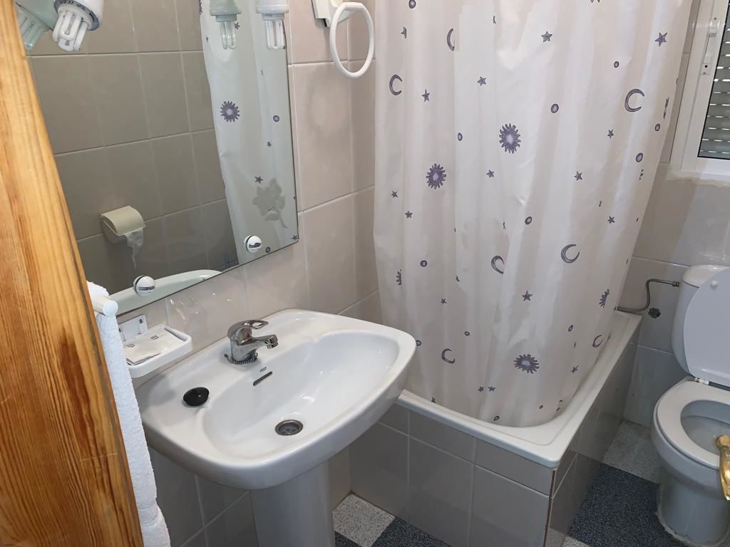 Een badkamer met een wit wastafel, een spiegel, een toilet en een douchegordijn met een sterren-en-maan dessin.