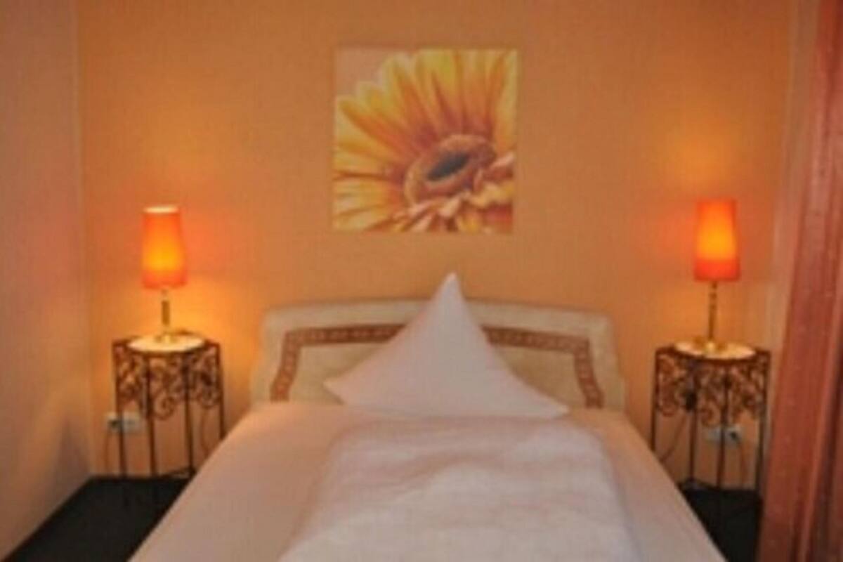 A hotel room with a bed, two bedside lamps, and a wall art piece.
