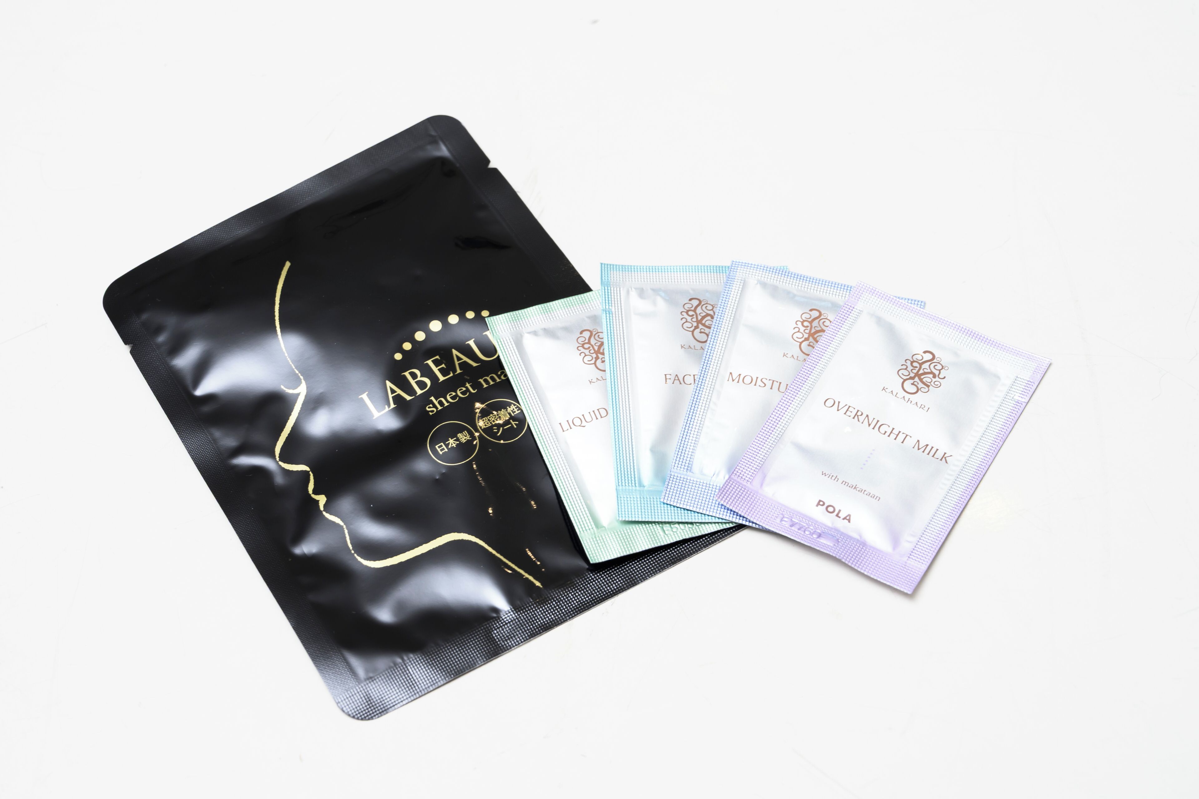 A black bag with gold lettering and several smaller bags with white and light blue packaging.