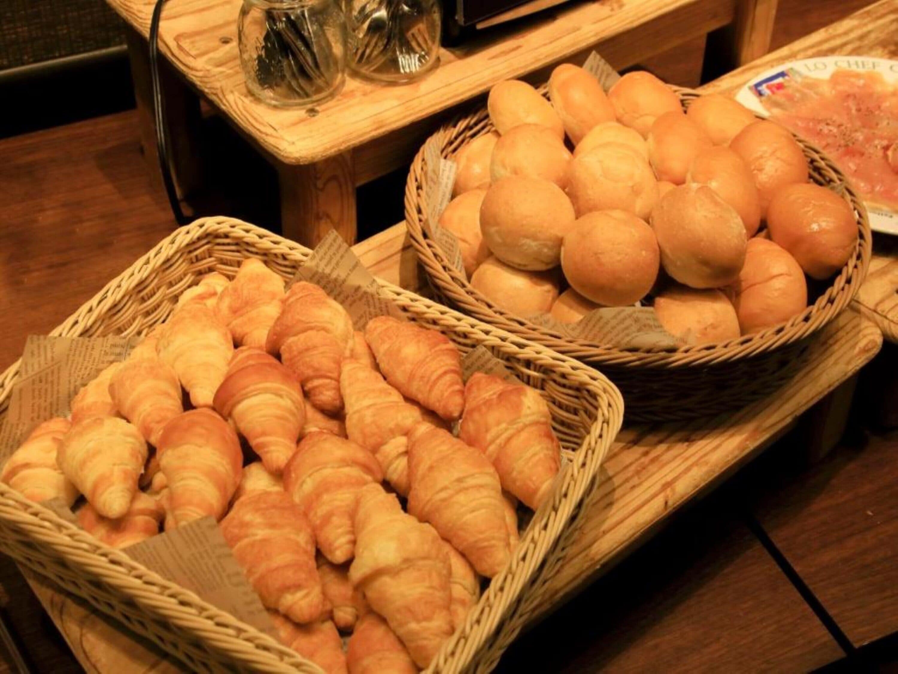 Two wicker baskets filled with bread, placed on a wooden table.