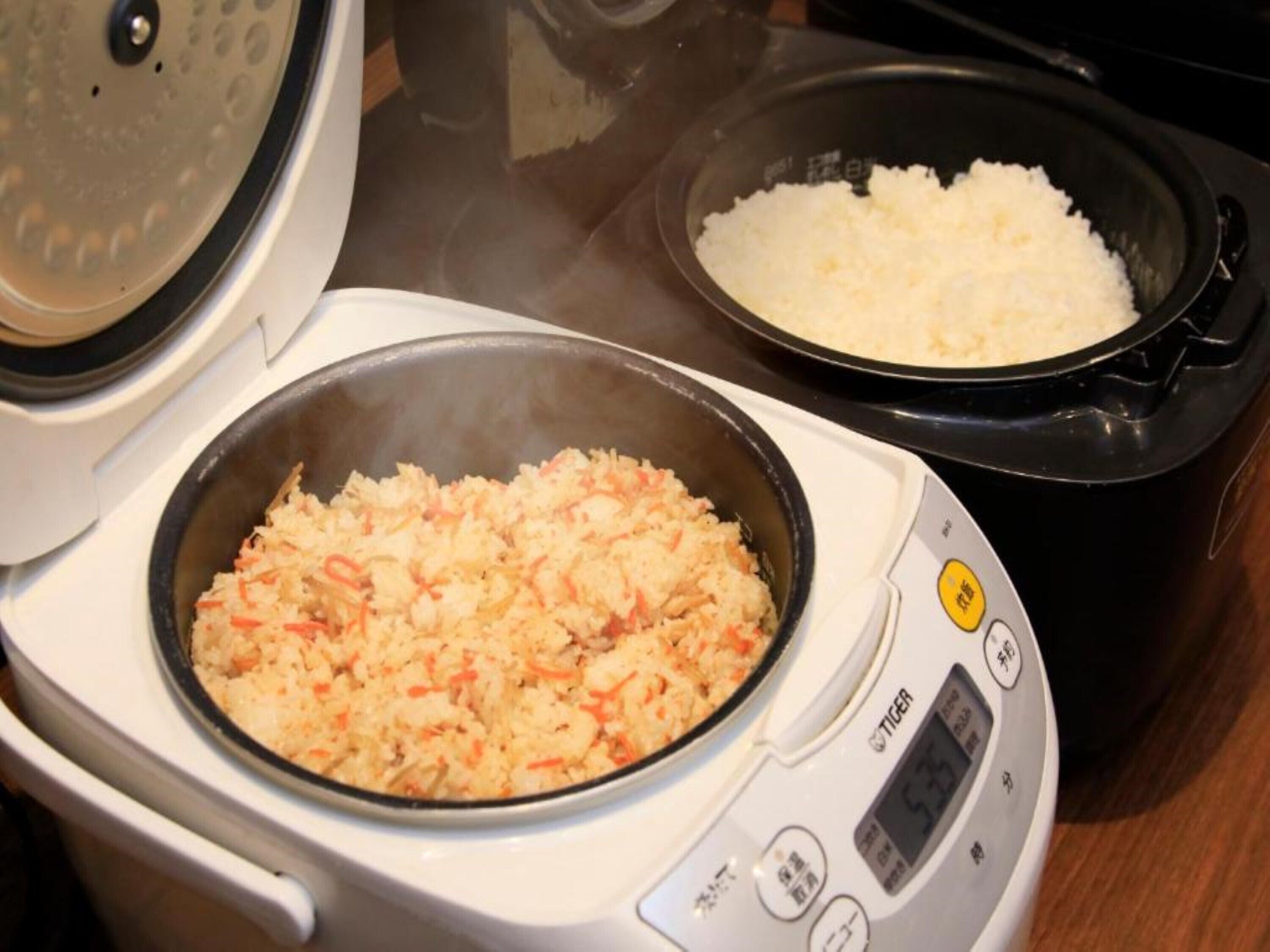 Una cocedora de arroz con dos preparaciones distintas: una con arroz y vegetales, y otra con arroz solo.