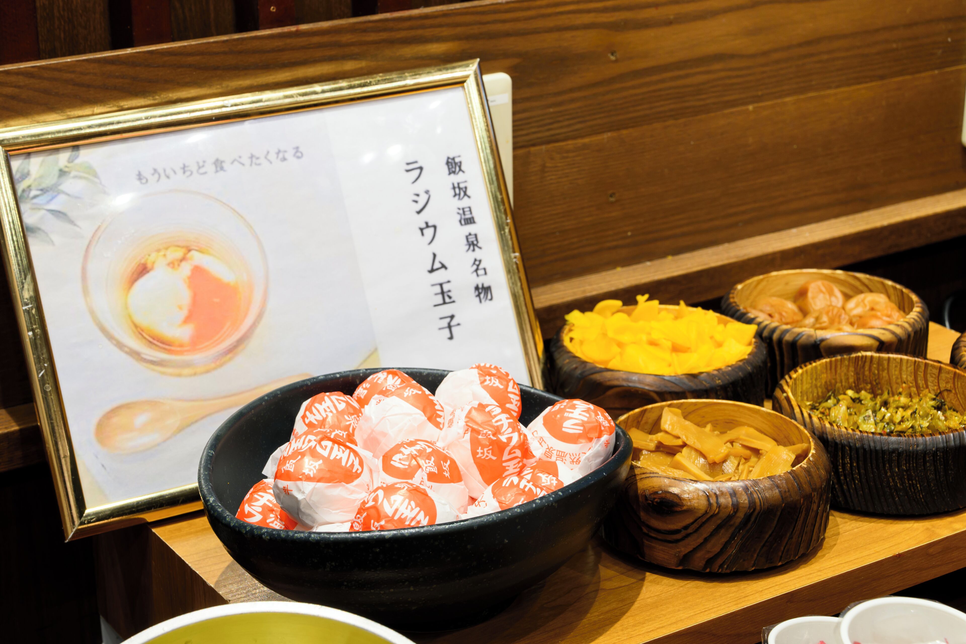 A table with various food items, including a bowl of wrapped sweets and other dishes.