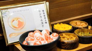 A table with various food items, including a bowl of wrapped sweets and other dishes.