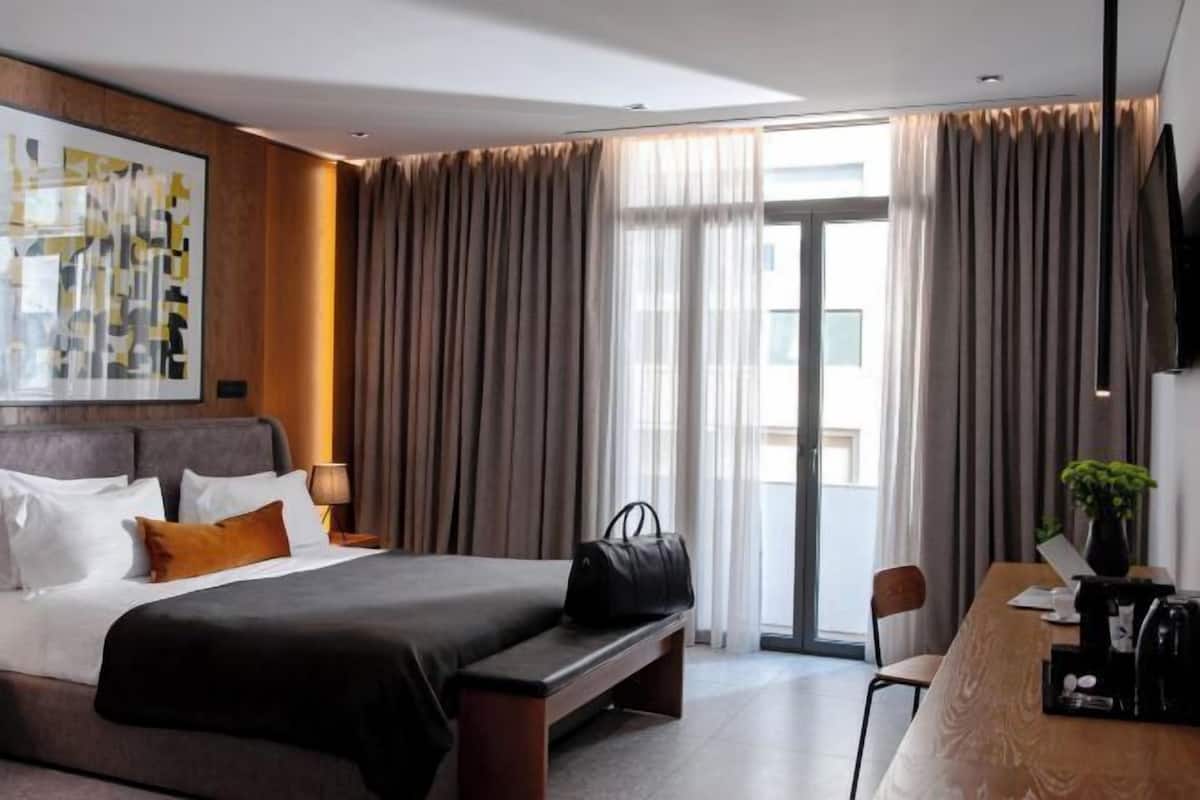 Habitación de hotel moderna con una cama grande, un escritorio y vistas al exterior.