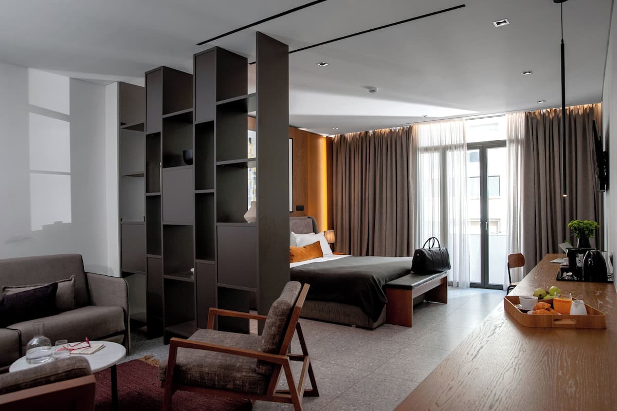 Una habitación de hotel moderna con cama, sofá y zona de comedor.