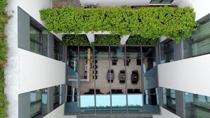 A modern building with a glass atrium, green plants on the upper level, and a view of the interior space below. - The Editor Hotel Athens (Athens)