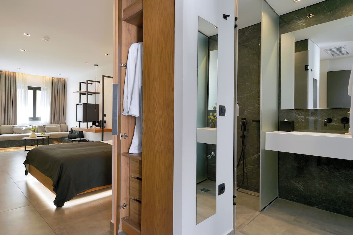 Una habitación de hotel moderna con una cama grande, un escritorio, un sofá y un baño con espejo y lavabo.