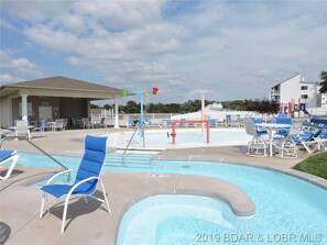 Relax by the pool surrounded by a fence, with lounge chairs and a shaded seating area.